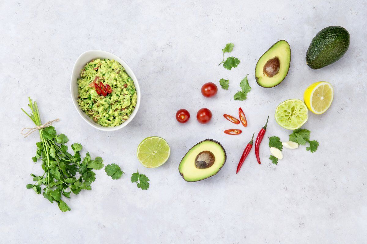 Avocado aufbewahren in vielen Formen: Guacamole im Schälchen und Avocados auf grauer Fläche Avocado aufbewahren in vielen Formen: Guacamole im Schälchen und Avocados auf grauer Fläche