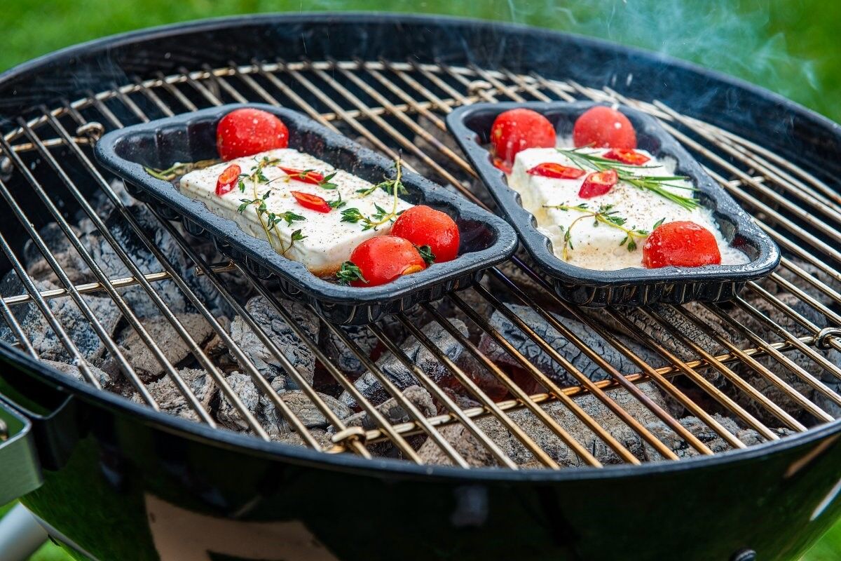 Zwei Grillschalen mit Käse und Tomate auf dem Grill für das vegetarische Grillen Zwei Grillschalen mit Käse und Tomate auf dem Grill für das vegetarische Grillen