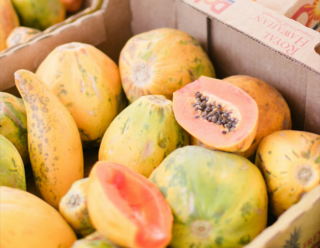 Ganze und halbierte Papayas in einer Obstkiste