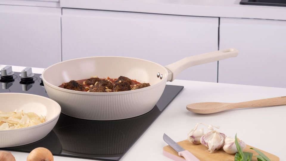 Essen wird in einer Keramikpfanne auf dem Kochfeld zubereitet