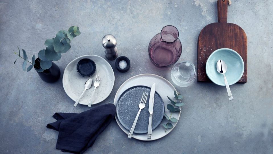 Modern gedeckter Tisch mit Schneidebrett, Karaffe, Salzstreuer & Co.