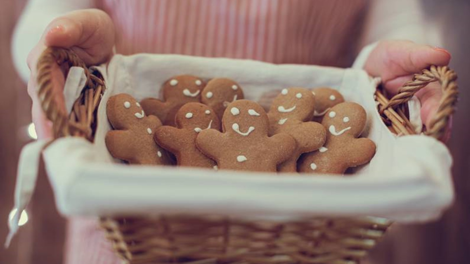 Lebkuchen-Männer in einem Weidenkorb, der von einer Frau gehalten wird Lebkuchen-Männer in einem Weidenkorb, der von einer Frau gehalten wird