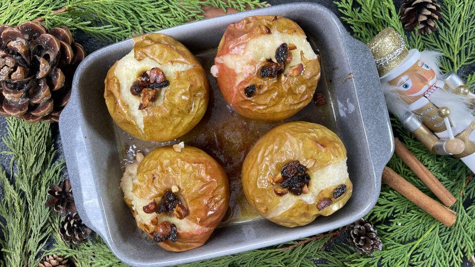 Vier Bratäpfel in einer Auflaufform, umrandet von Tannenzweigen