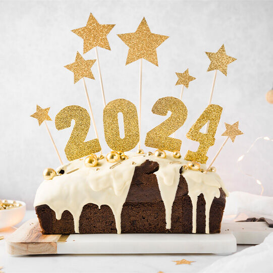 Silvester-Kuchen mit goldener Deko auf einem Servierbrett