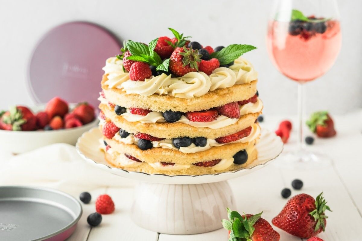 Sommerkuchen mit frischen Beeren und Creme auf einer Tortenplatte Sommerkuchen mit frischen Beeren und Creme auf einer Tortenplatte
