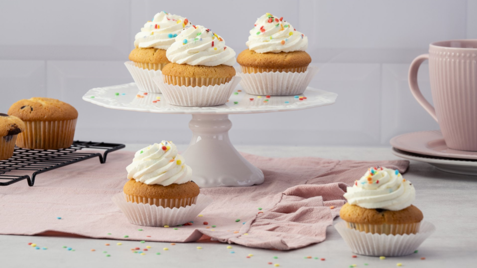 Muffins mit Sahne-Haube und Streuseln auf und neben einer Etagere Muffins mit Sahne-Haube und Streuseln auf und neben einer Etagere
