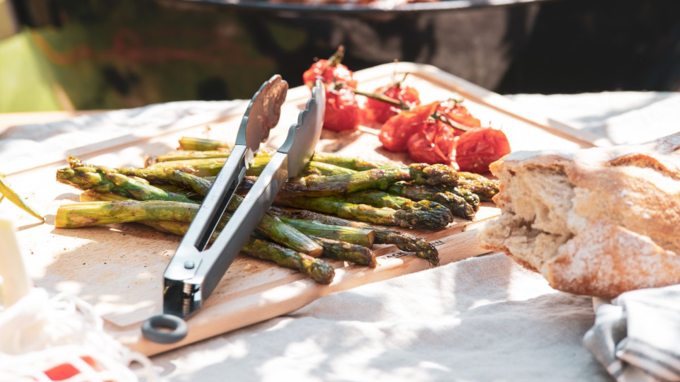Gegrillter, grüner Spargel - darüber eine Grillzange